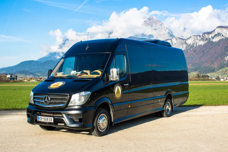 Schwarzer Mercedes Sprinter VIP-Bus von Schreder – Seitenansicht vor den Alpen